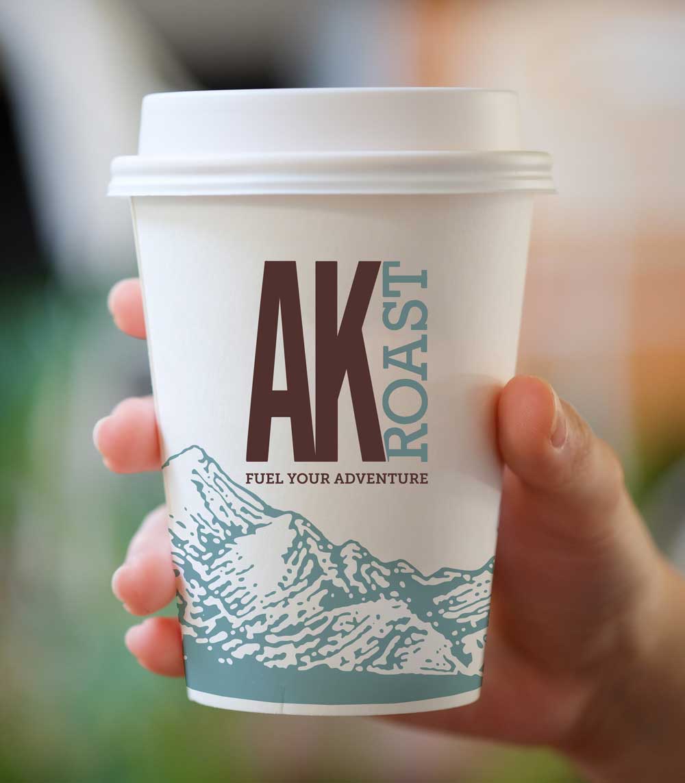 Hand holding AK Roast coffee cup